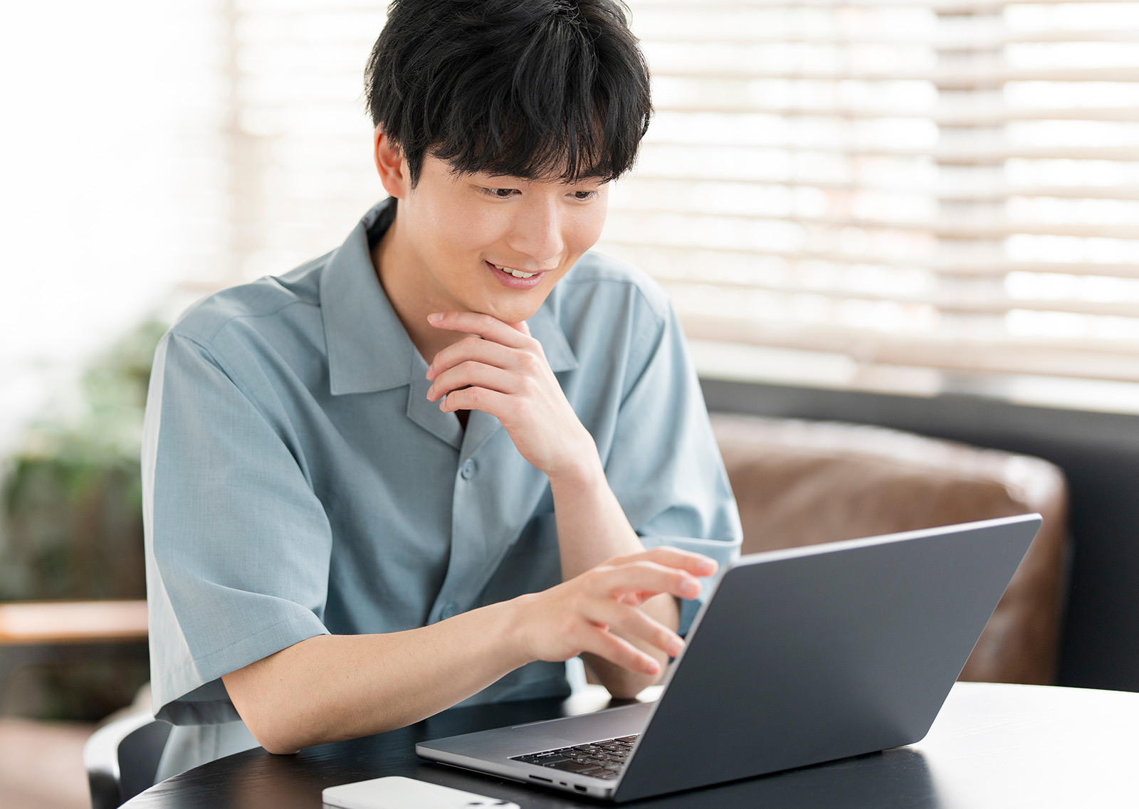 若い日本人男性がノートパソコンを開き作業を